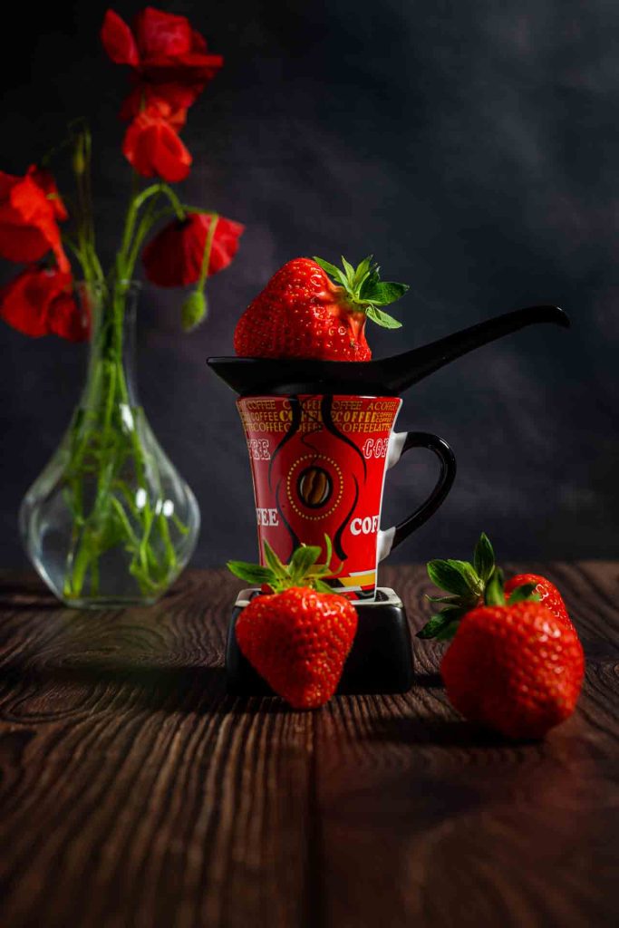 Photos fruits et légumes. Une fraise dans une petite tasse à café rouge.